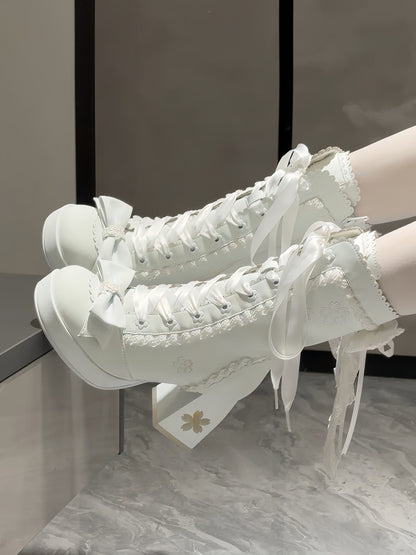 White high-heeled shoes with lace details on a neutral background