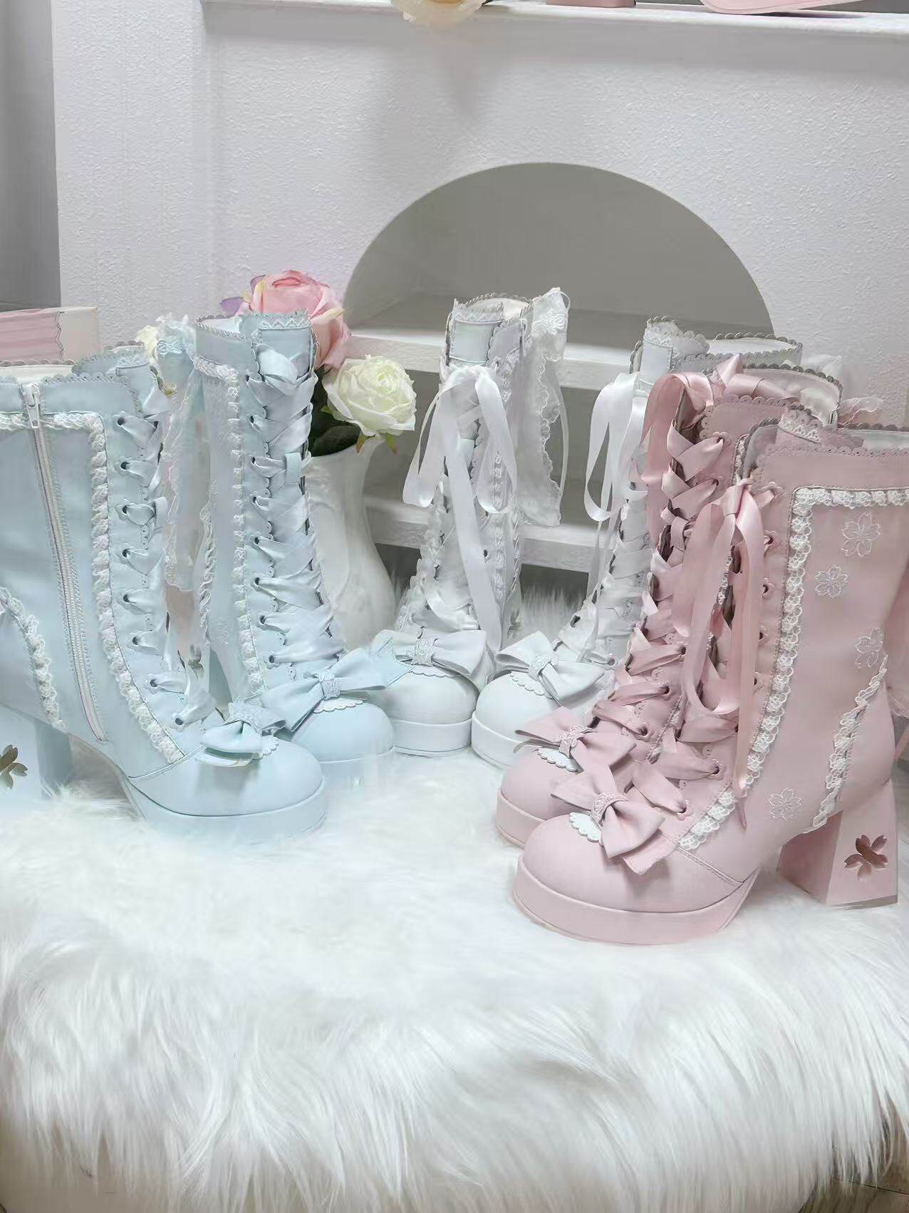 Pair of light blue and pink high-top sneakers with decorative cherry blossom sakura laces on a white surface.