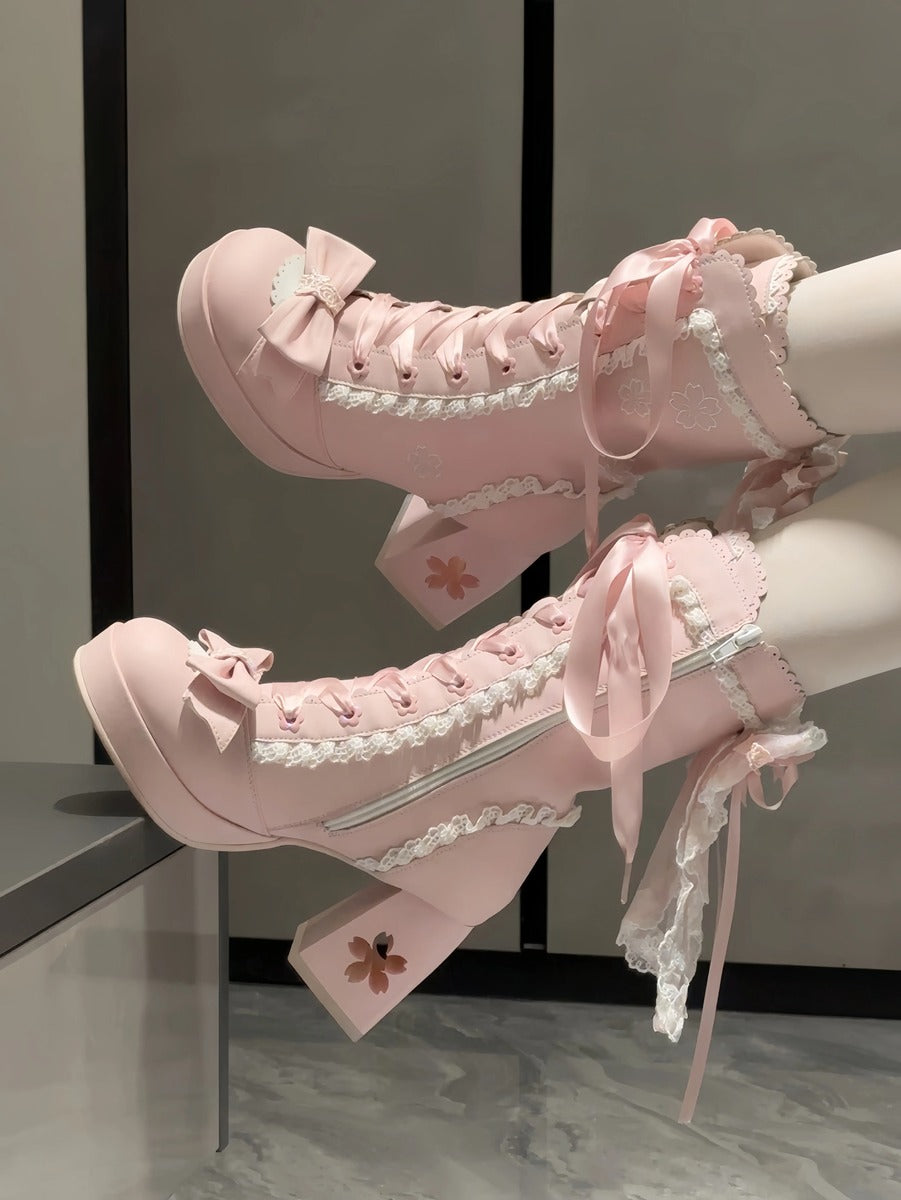 Pink high-heeled boots with lace details on a neutral background