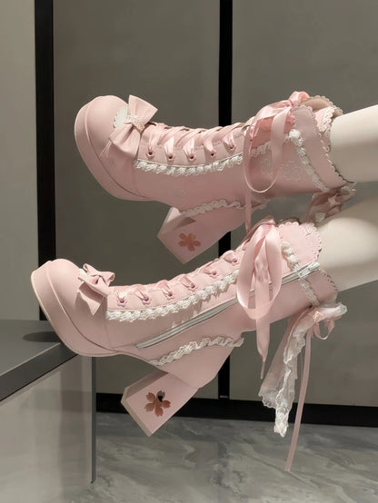 Pink high-heeled boots with lace details on a neutral background