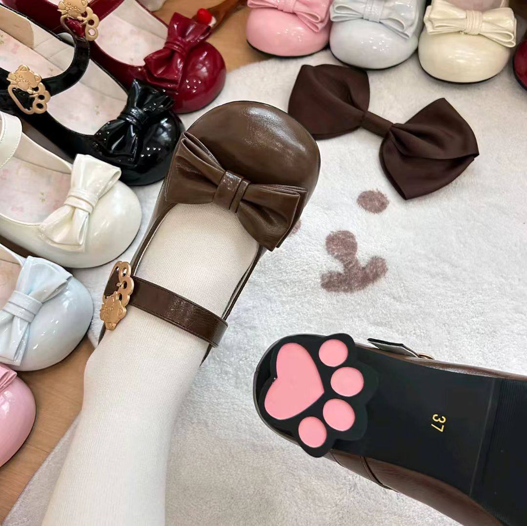 Collection of children's shoes with bows and a paw print sandal on a white surface.