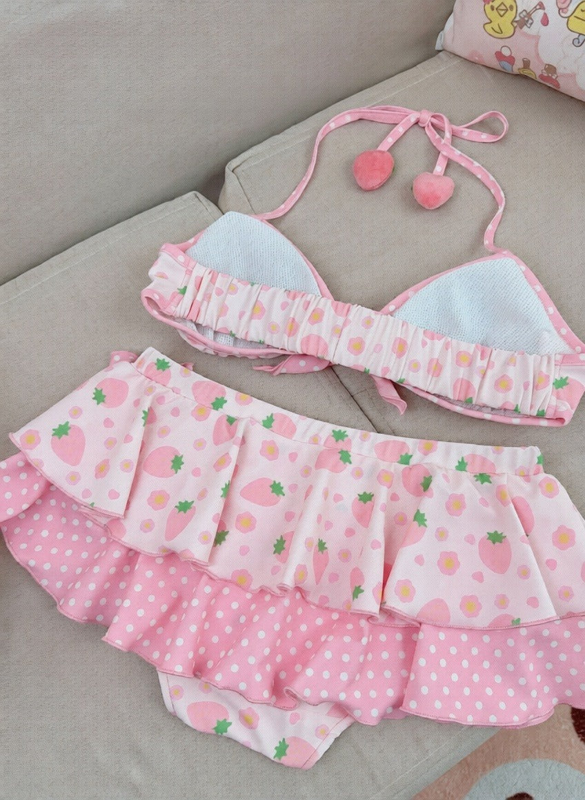 Pink children's swimsuit with strawberry pattern on a gray surface