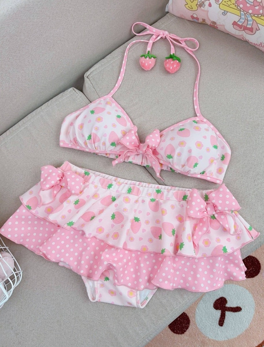 Pink bikini set with strawberry pattern on a gray surface