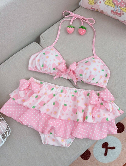 Pink bikini set with strawberry pattern on a gray surface