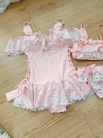 Pink swimsuit set with ruffles and lace on a wooden floor.