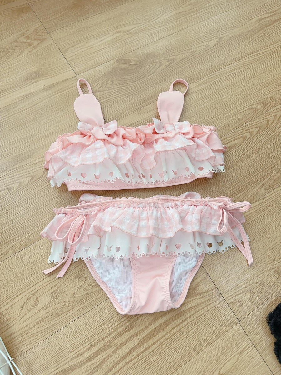 Pink swimsuit bikini set with ruffles on a wooden floor