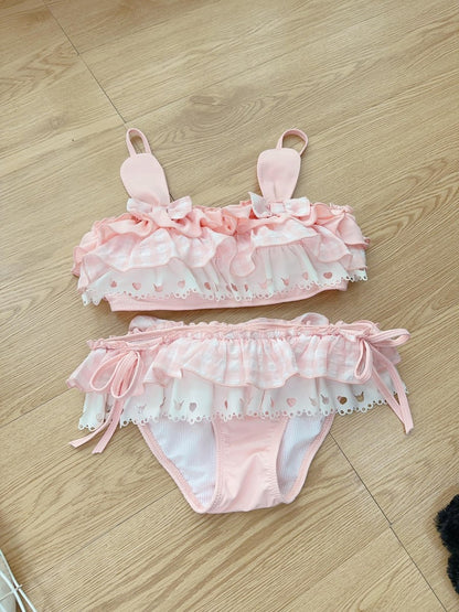 Pink swimsuit bikini set with ruffles on a wooden floor