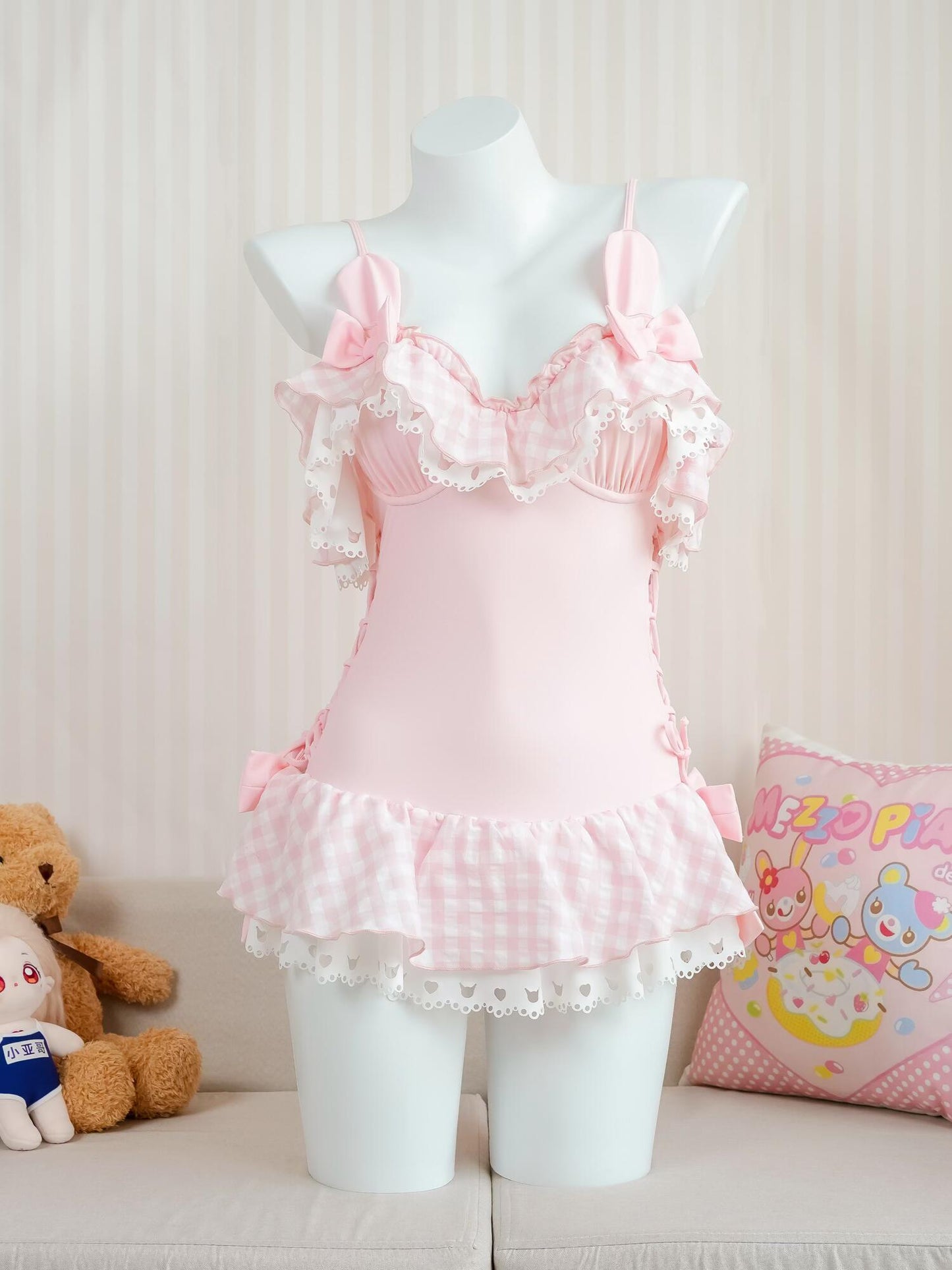 Pink swimsuit outfit with ruffles on a mannequin against a light background