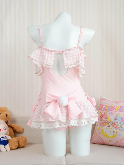 Pink swimsuit dress on a mannequin with a teddy bear and pillow in the background