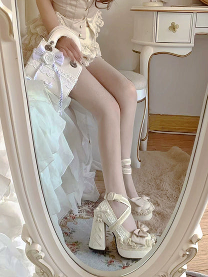 Person wearing white lace shoes and stockings sitting on a chair in front of a mirror.