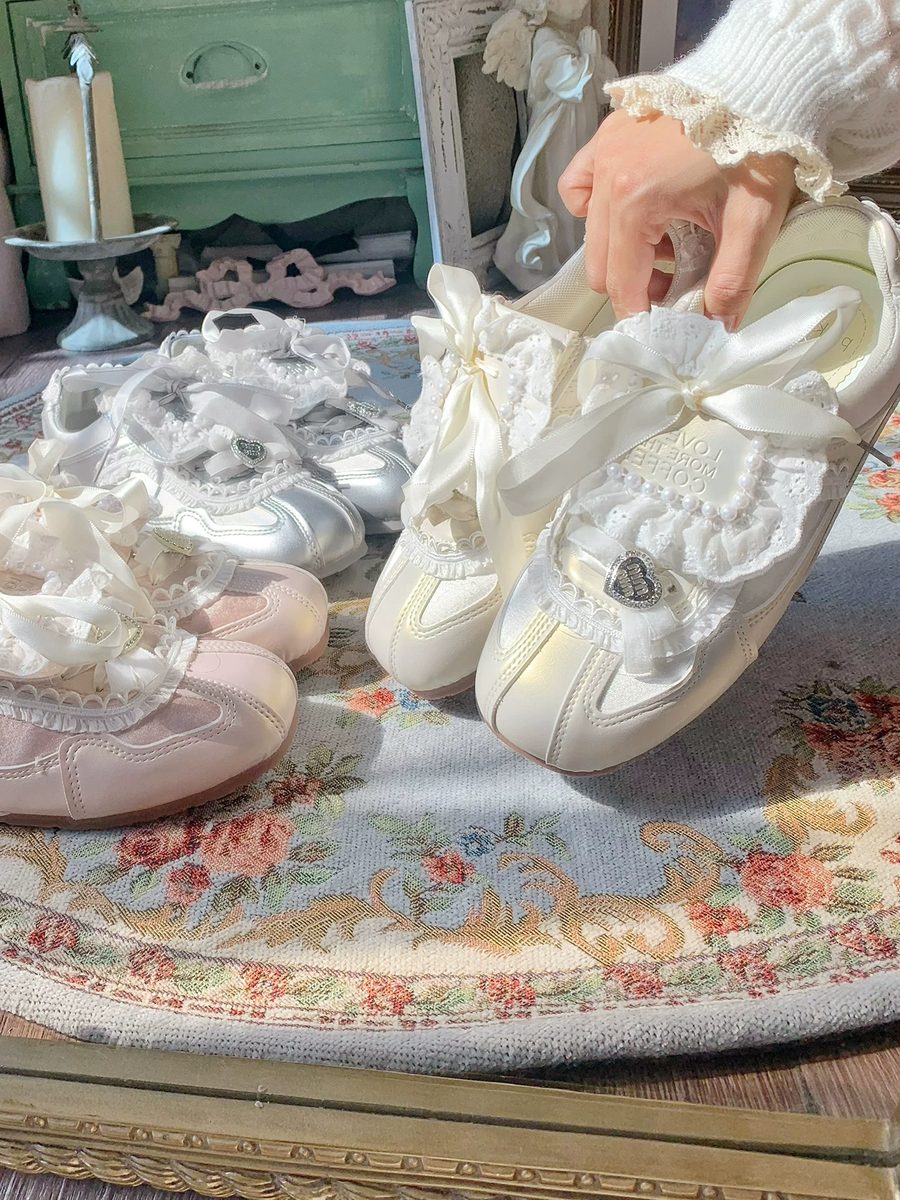 Pair of white lace-up shoes with decorative elements on a floral-patterned surface.