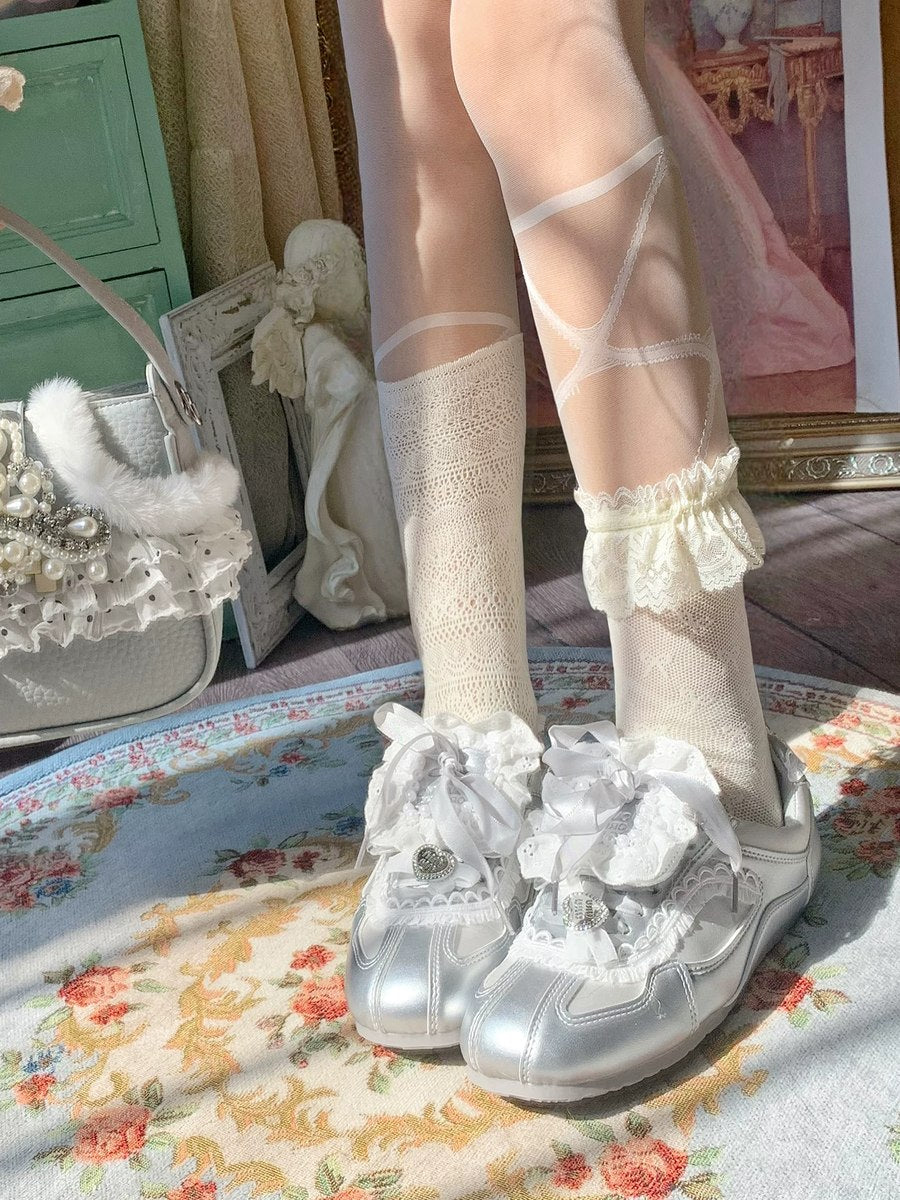 White sneakers with floral decorations worn with sheer white socks on a patterned rug.