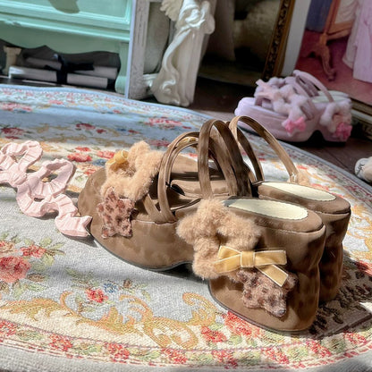 Pair of brown sandals with decorative bows on a floral-patterned surface.