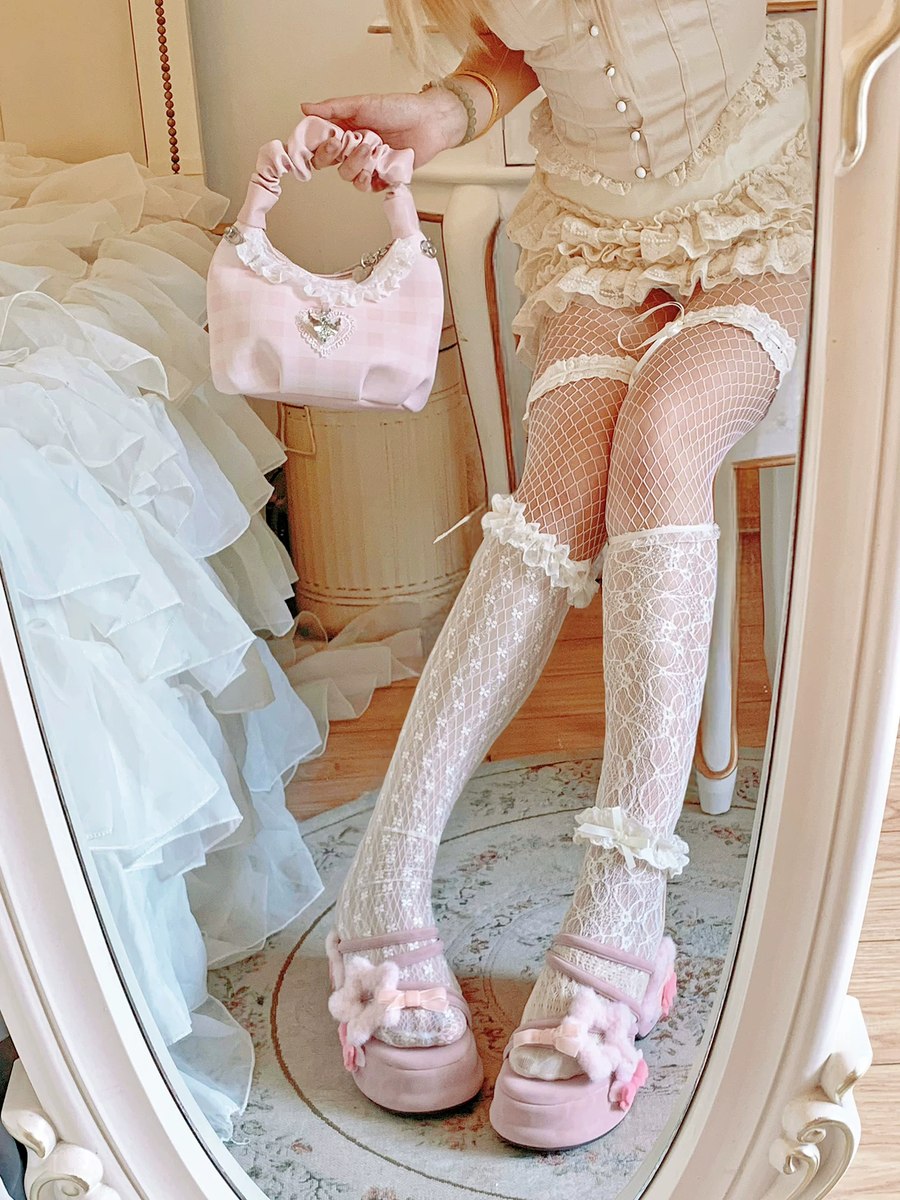 Person wearing a vintage-style outfit with lace stockings and holding a small pink handbag.
