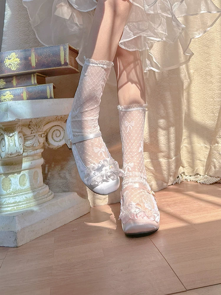 White lace-up shoes worn with sheer white stockings on a wooden floor.