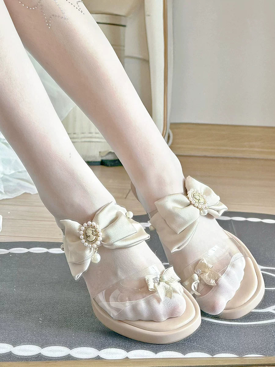 White sandals with decorative bows and flowers on a neutral background
