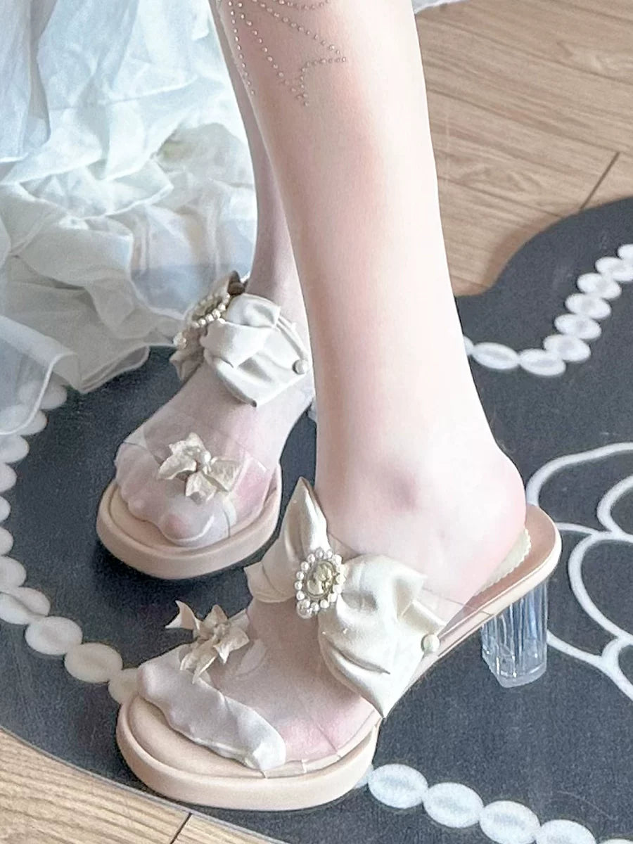 White sandals with floral decorations on a black and white patterned rug.