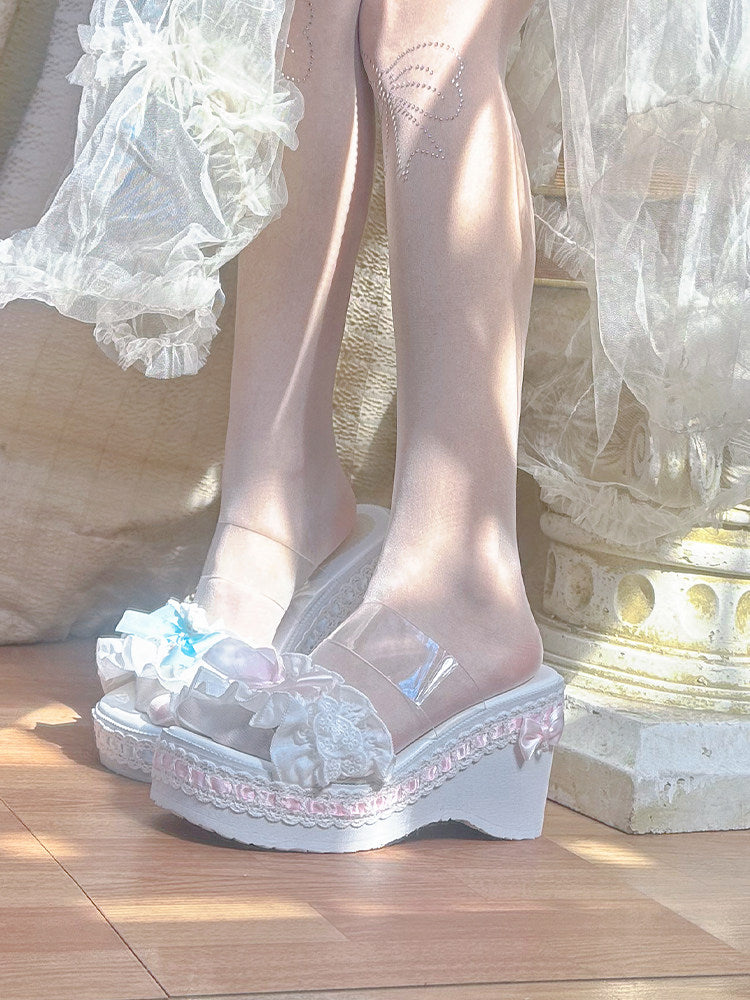 Transparent platform shoes with decorative elements worn by a person in a white dress.