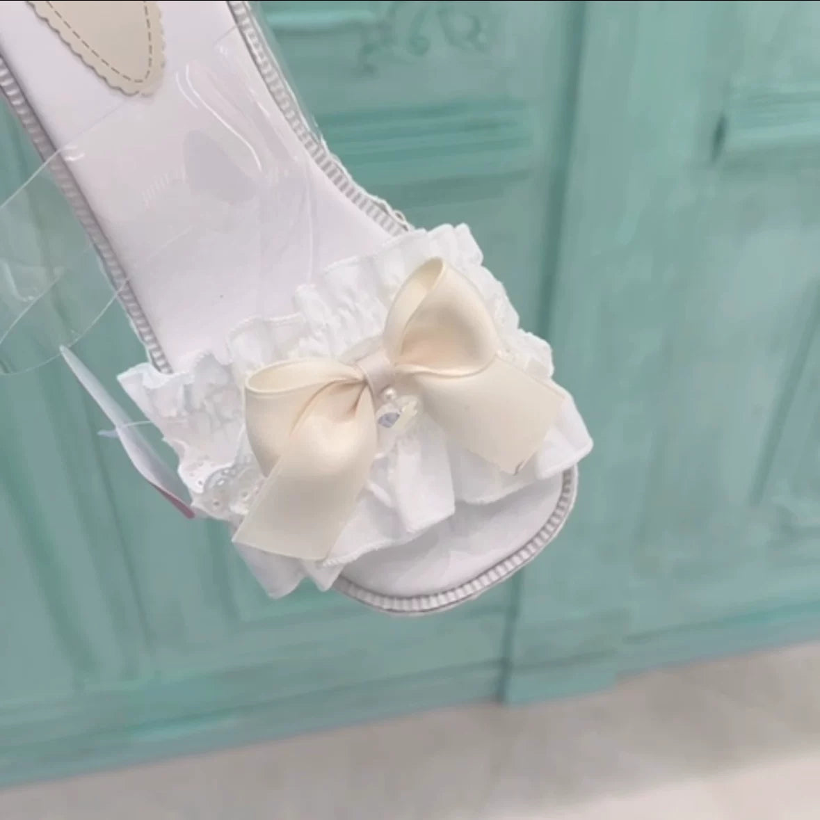White sandal with a large bow on a light blue background