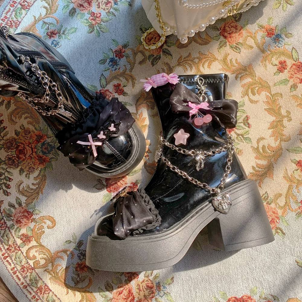 Black platform boots with decorative chains and bows on a floral fabric background