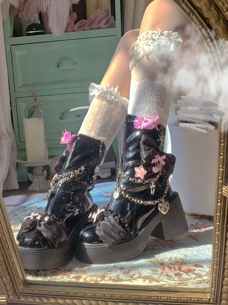 Black platform boots with floral and chain details worn by a person, reflected in a mirror.
