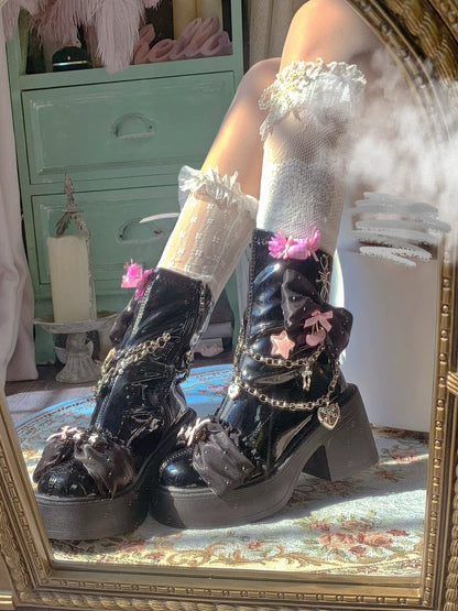 Black platform boots with floral and chain details worn by a person, reflected in a mirror.
