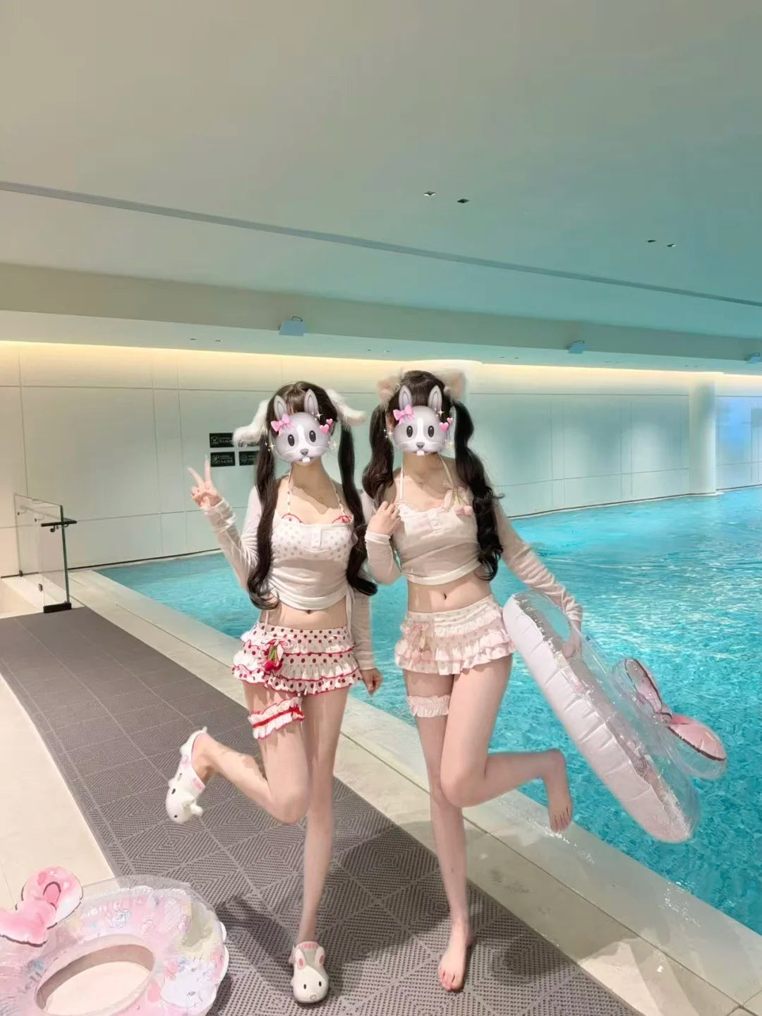 Two people in matching outfits with cat ears posing by a pool.