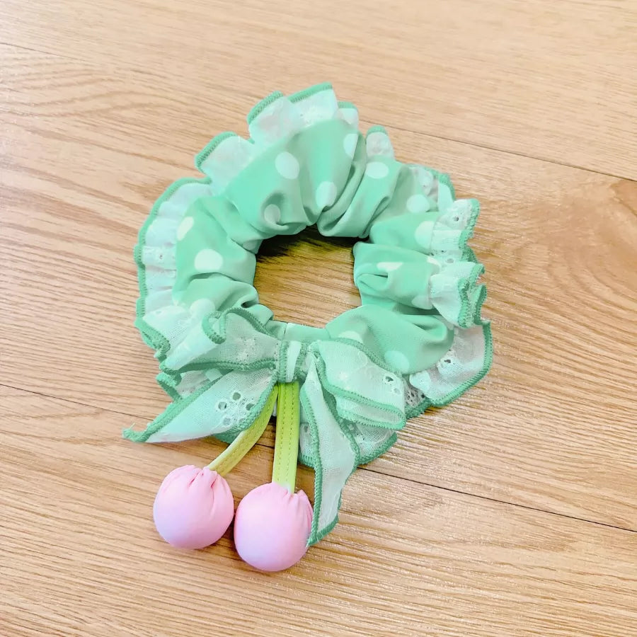Green scrunchie with pink berries on a wooden surface