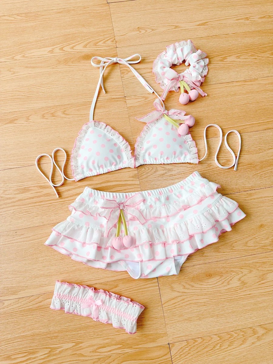 Pink and white polka dot bikini set with matching headbands on a wooden floor.