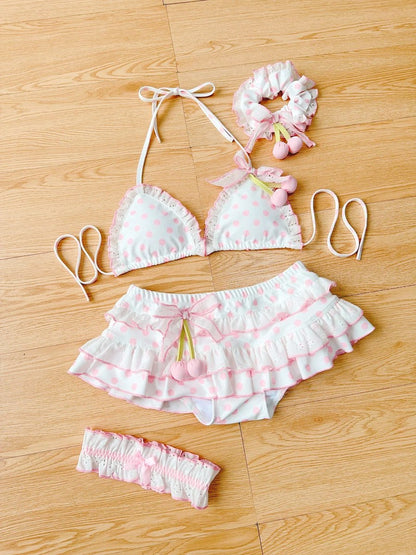 Pink and white polka dot bikini set with matching headbands on a wooden floor.