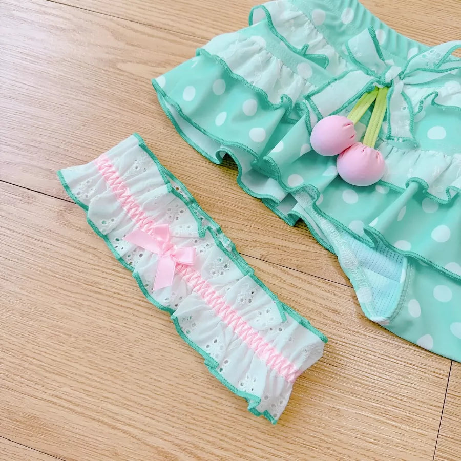 Green polka dot outfit with pink details on a wooden surface