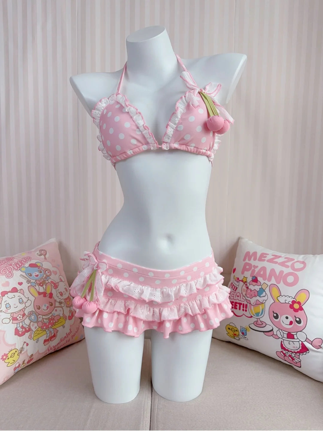 Pink polka dot bikini set on a mannequin with cartoon-themed pillows in the background