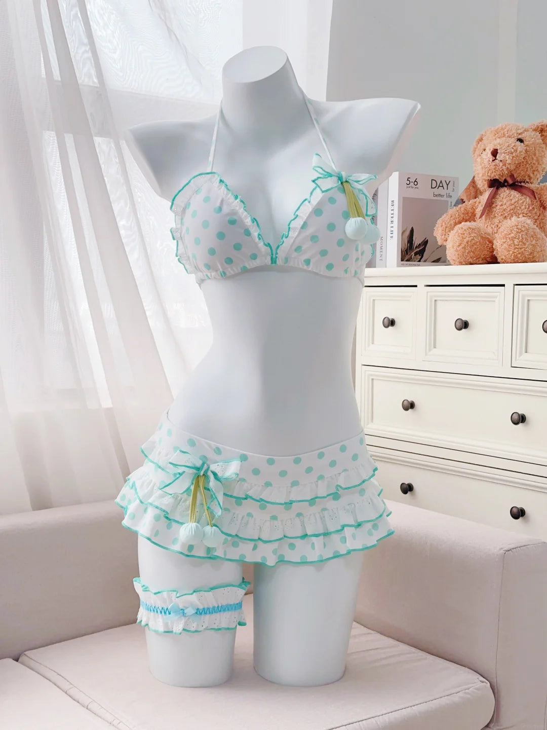 Mannequin wearing a polka dot bra and panties set with a teddy bear and dresser in the background.