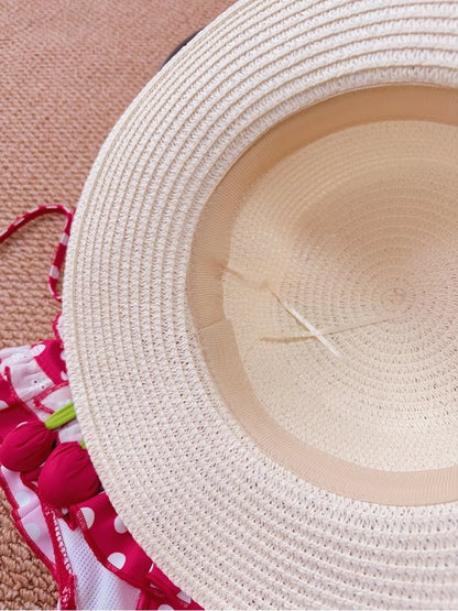 Close-up of a straw hat with a pink floral fabric underneath