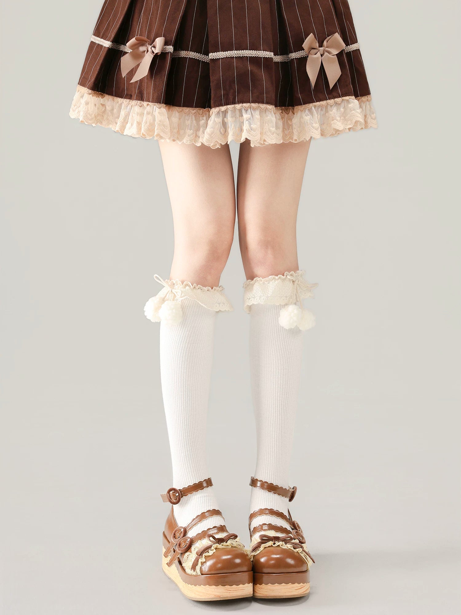 Person wearing a brown pinstripe dress with lace trim, white stockings, and brown shoes on a light gray background.