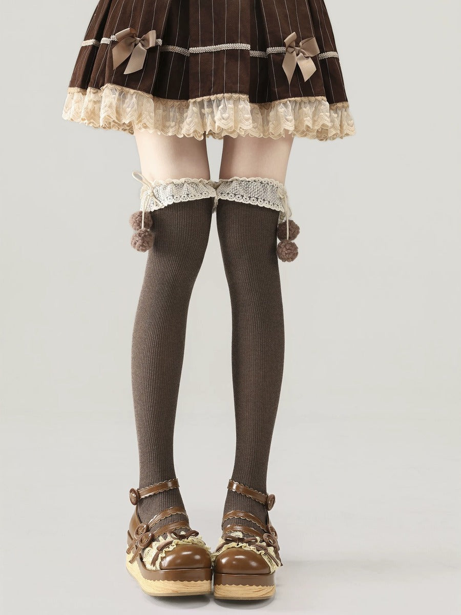 Person wearing a brown and beige outfit with lace details on a plain background