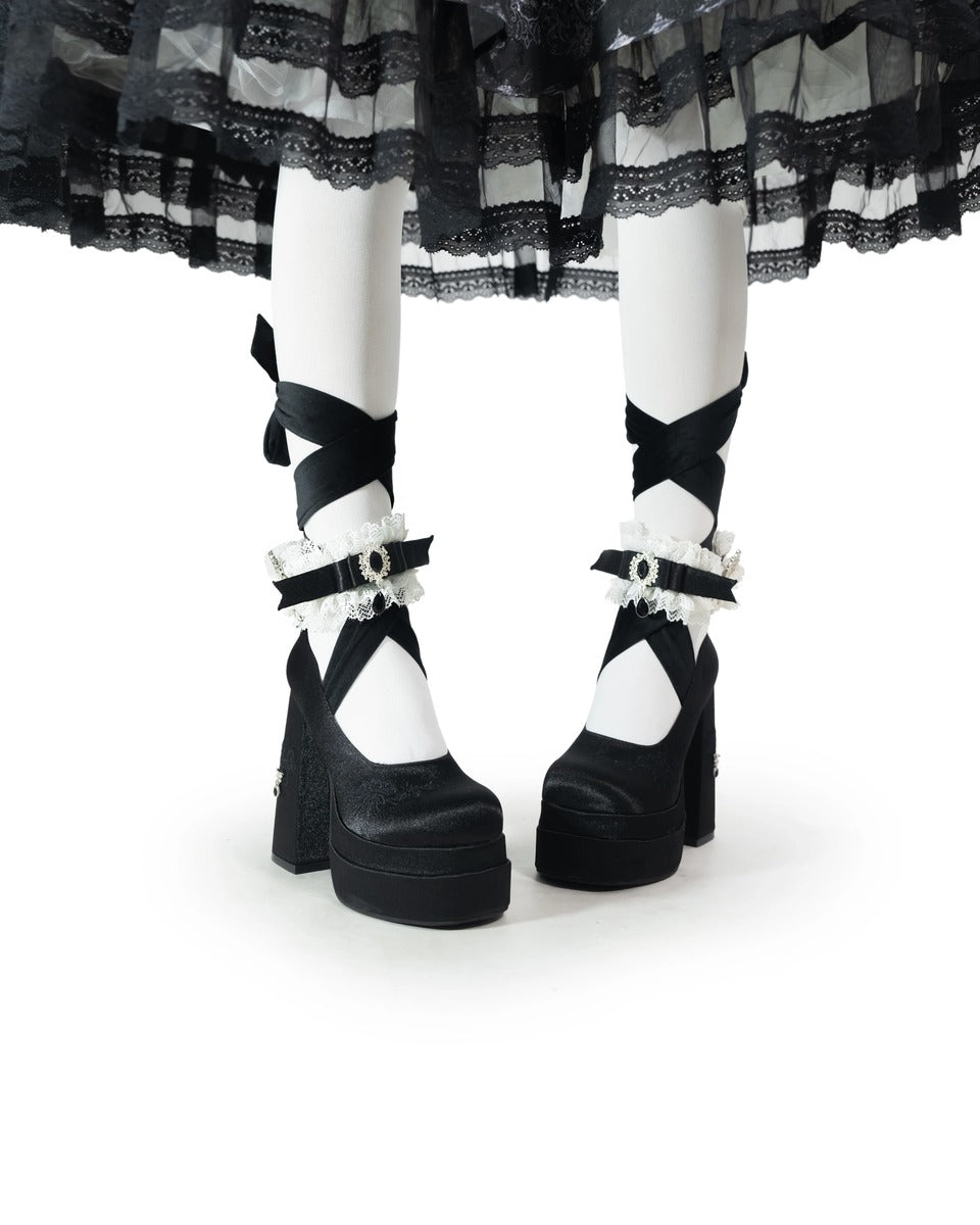 Black and white platform shoes with decorative straps on a white background