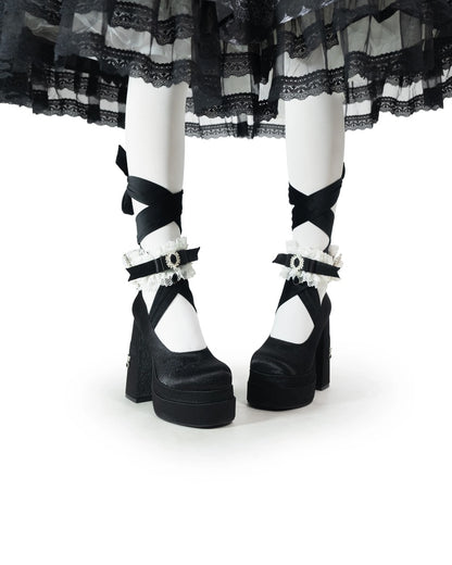 Black and white platform shoes with decorative straps on a white background
