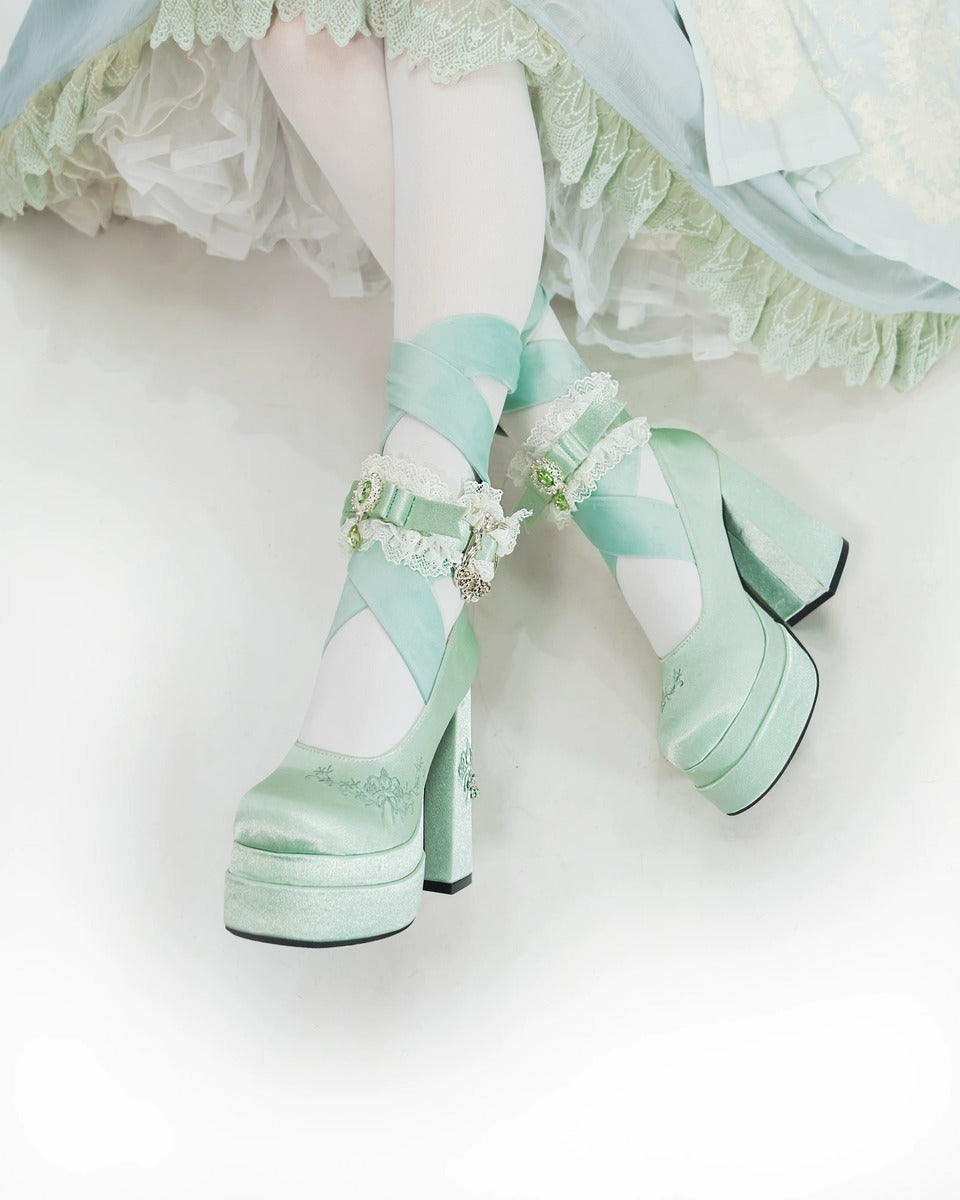 Pastel green platform shoes with decorative elements on a white background