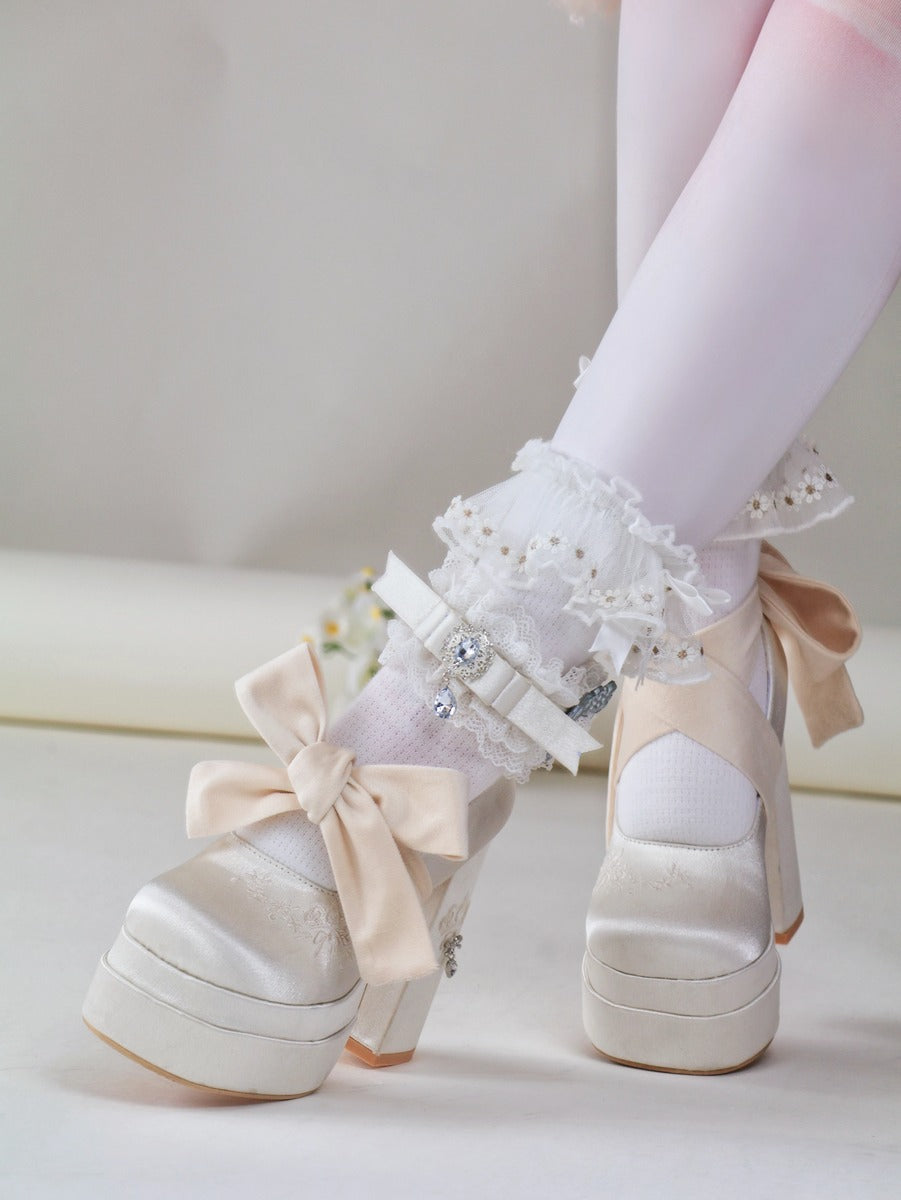 White platform shoes with bows and lace details on a light background