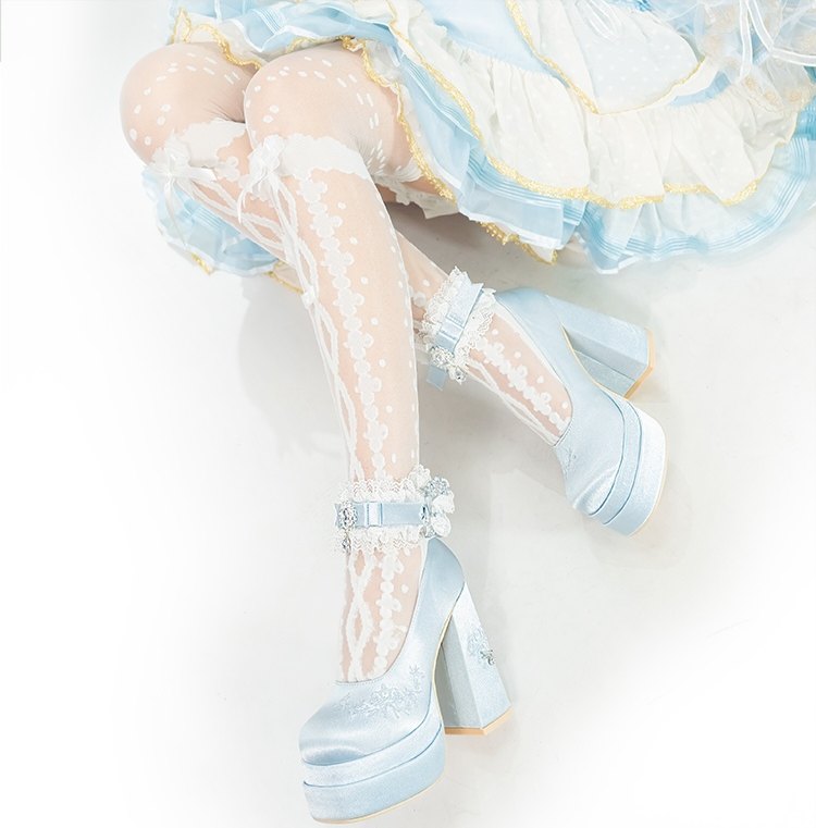 Light blue high-heeled shoes with decorative straps worn with a pastel outfit.