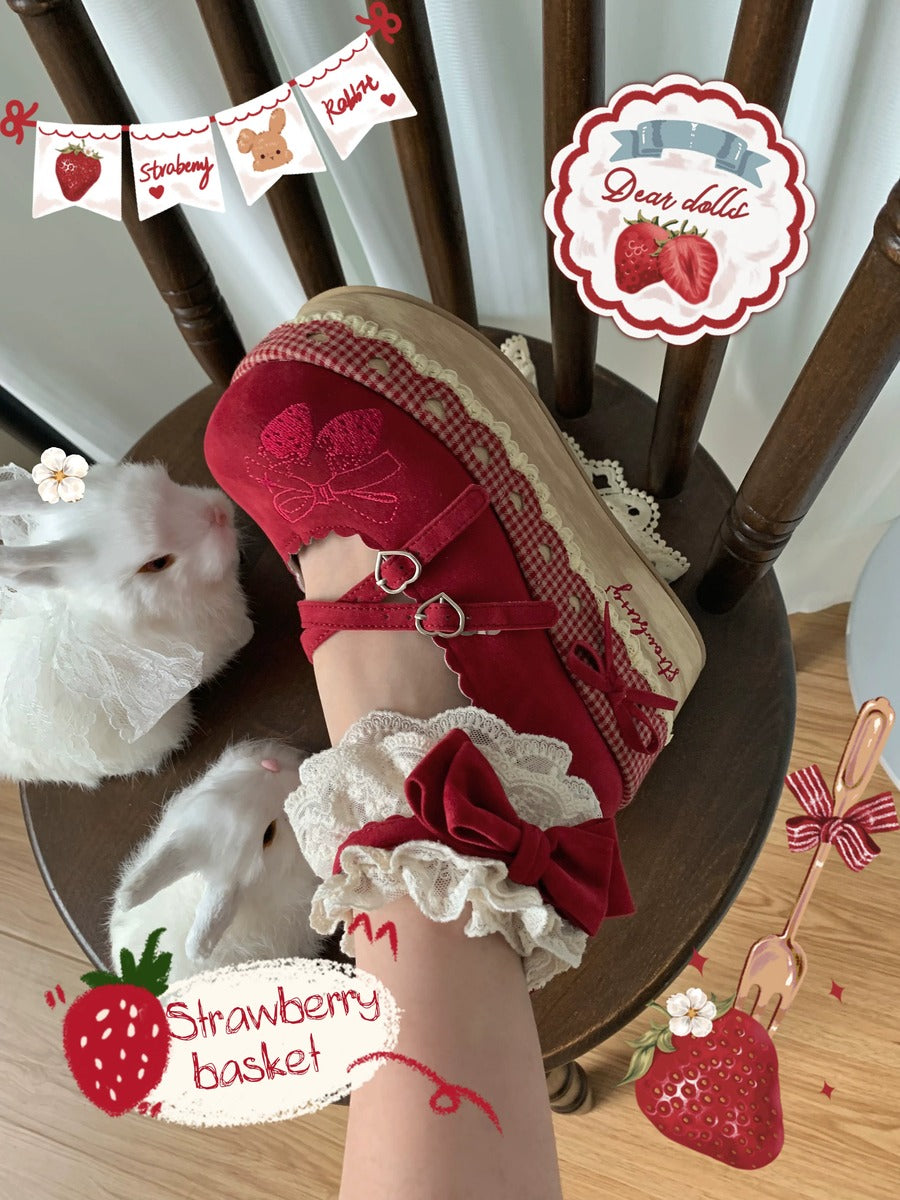 Red sandal with white lace and bow on a wooden chair, surrounded by strawberry-themed decorations.