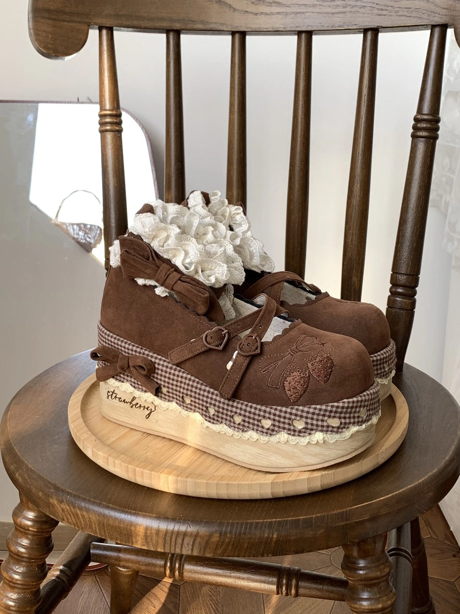 Pair of brown children's shoes with checkered details on a wooden chair.