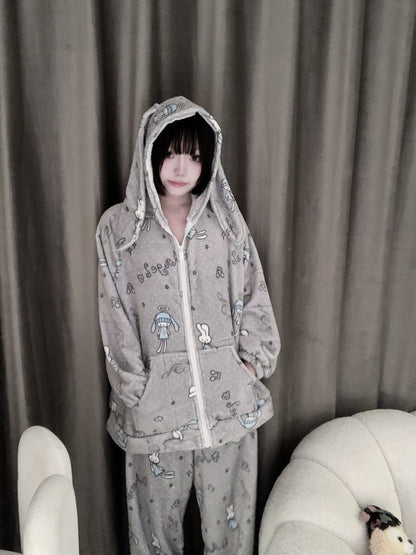 Person wearing a gray hoodie and pants with cartoon characters in front of a curtain.