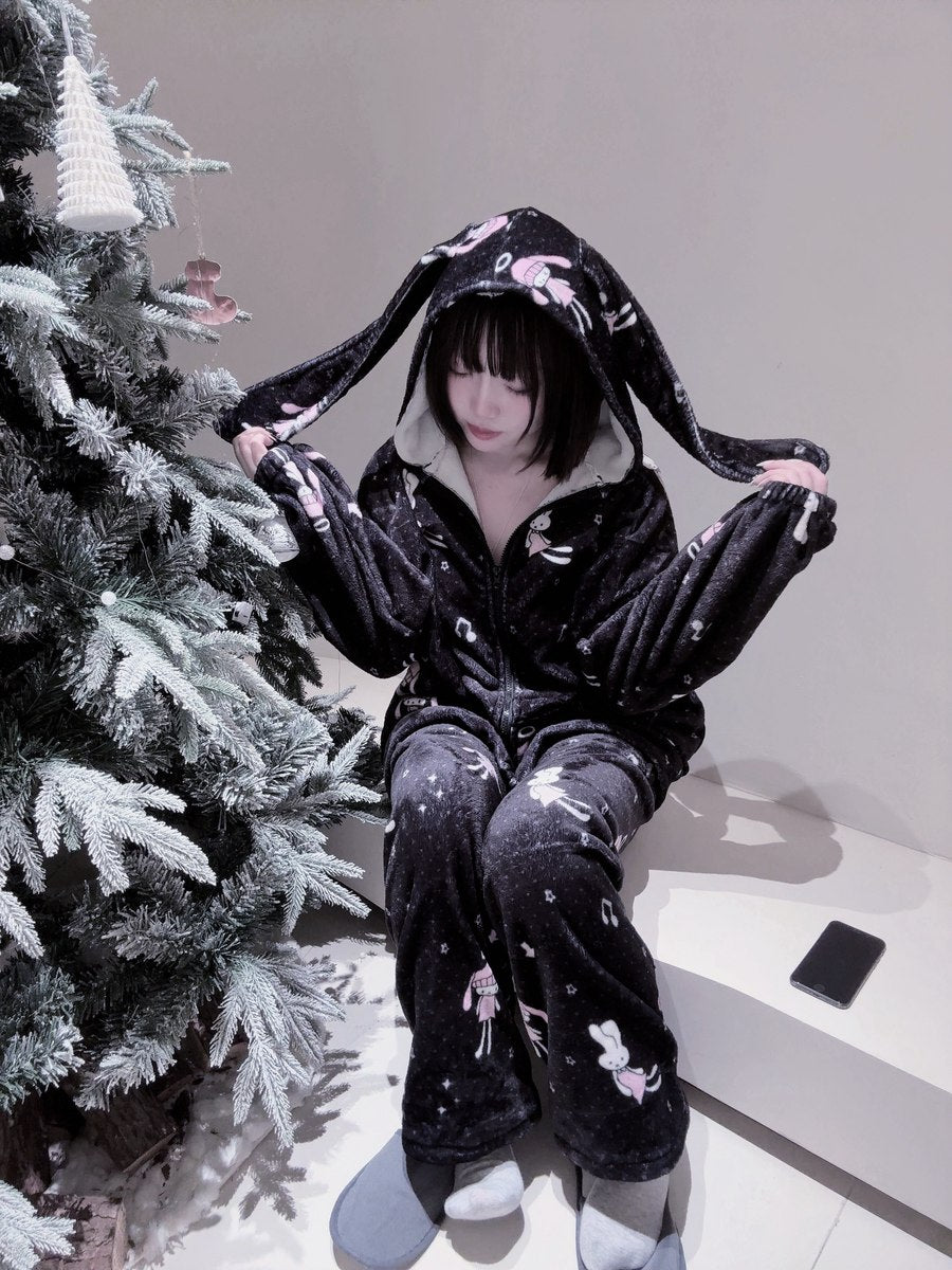Person wearing a black plushie-style outfit with long ears next to a decorated Christmas tree.