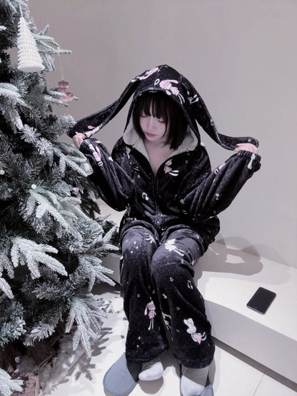 Person wearing a black plushie-style outfit with long ears next to a decorated Christmas tree.