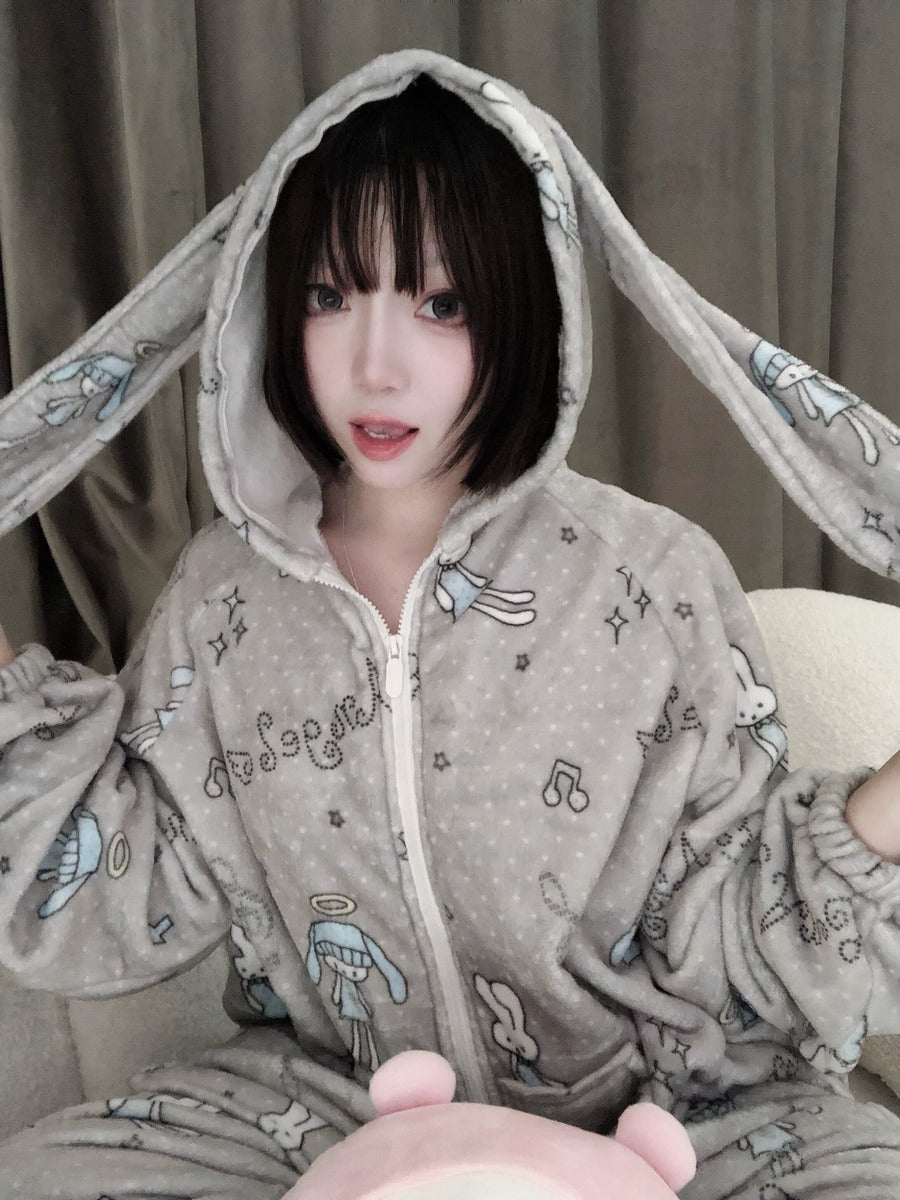 Person wearing a gray onesie with cartoon designs, sitting on a couch.