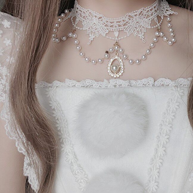 Close-up of a person wearing a delicate lace top and pearl necklace.