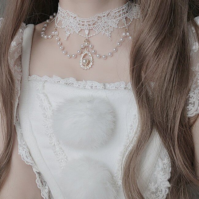 Close-up of a person wearing a white lace top and pearl necklace.