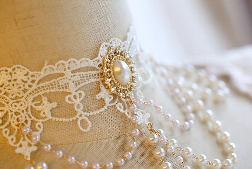 Pearl necklace with a decorative clasp on a lace garment